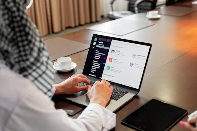 Person using a laptop at a table with a tablet beside them